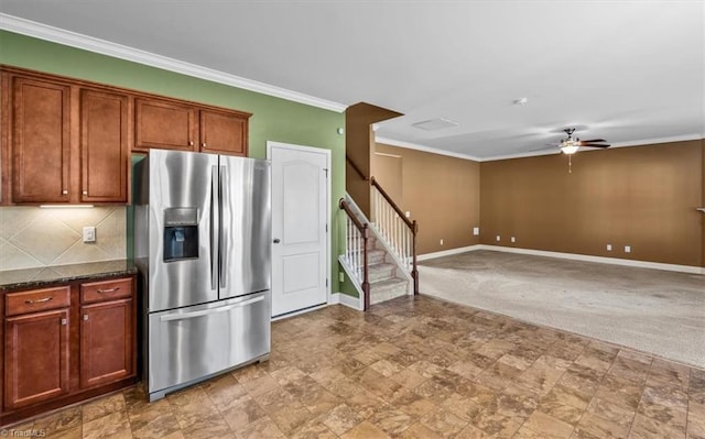 kitchen featuring tasteful backsplash, stainless steel refrigerator with ice dispenser, ceiling fan, crown molding, and dark stone countertops