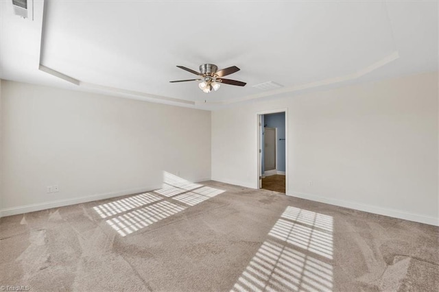 carpeted empty room featuring ceiling fan and a raised ceiling