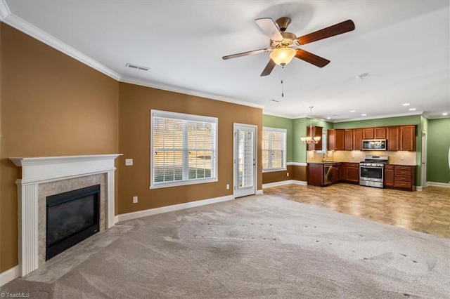 unfurnished living room with a tiled fireplace, light colored carpet, sink, ceiling fan, and crown molding