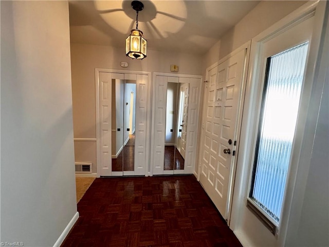 doorway with ceiling fan and dark parquet floors