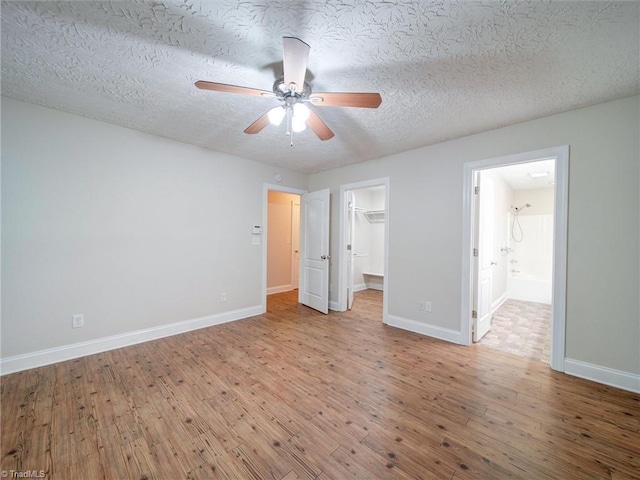 unfurnished bedroom featuring hardwood / wood-style flooring, ceiling fan, a spacious closet, a textured ceiling, and a closet