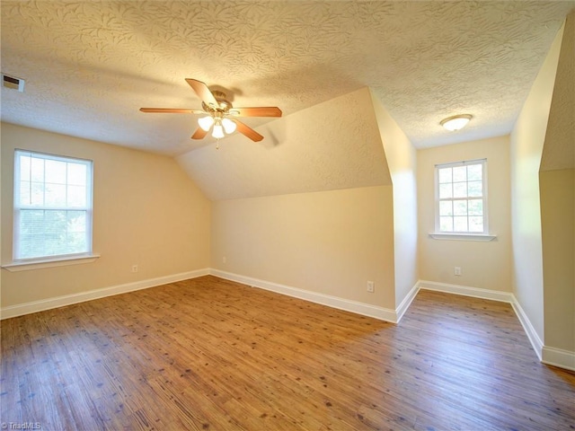 additional living space featuring hardwood / wood-style floors, ceiling fan, lofted ceiling, and a textured ceiling