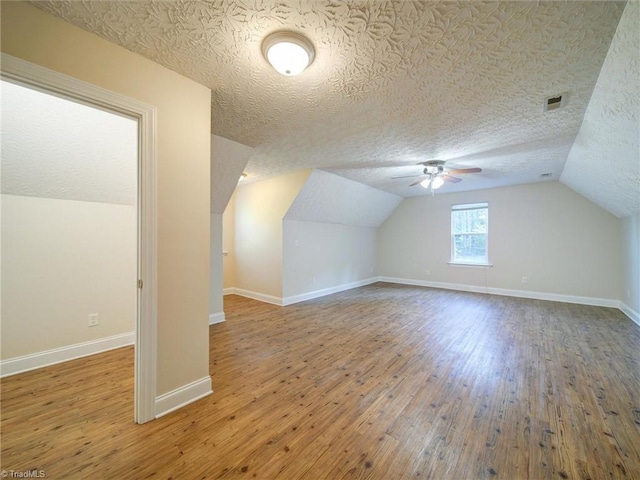 additional living space featuring hardwood / wood-style flooring, ceiling fan, a textured ceiling, and vaulted ceiling