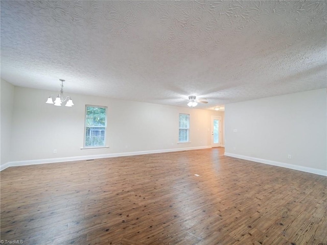 empty room with a textured ceiling, hardwood / wood-style flooring, and a notable chandelier