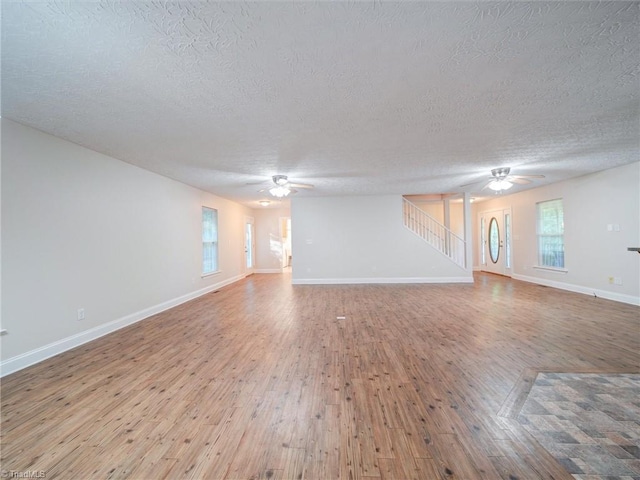 unfurnished living room with ceiling fan, a textured ceiling, and hardwood / wood-style flooring