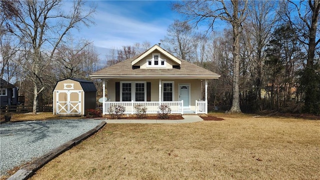 bungalow-style house featuring a front yard, covered porch, an outdoor structure, and a shed