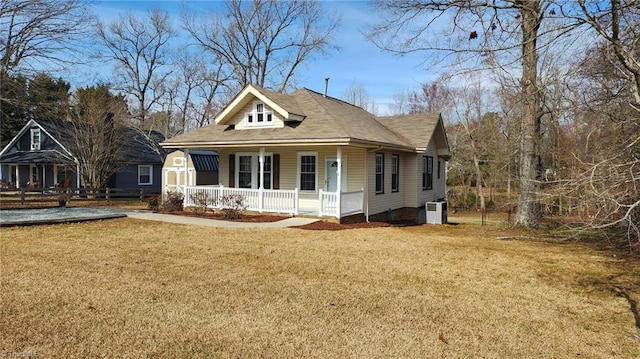 view of front of home featuring cooling unit, covered porch, and a front lawn