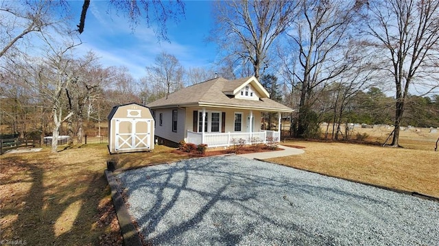 view of front facade with a storage unit, covered porch, a front yard, an outdoor structure, and driveway