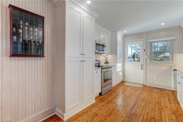 kitchen featuring white cabinetry, tasteful backsplash, stainless steel appliances, and light hardwood / wood-style flooring