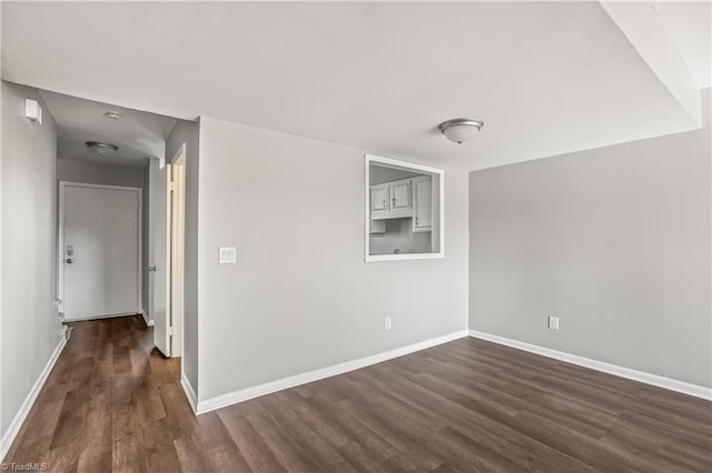 unfurnished room with dark wood-type flooring and baseboards