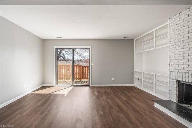 unfurnished living room featuring built in shelves, a fireplace, baseboards, and wood finished floors