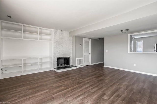 unfurnished living room with a brick fireplace, baseboards, visible vents, and wood finished floors