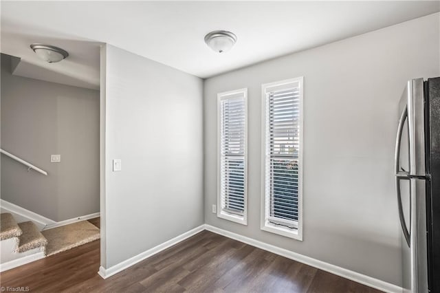 spare room featuring dark wood-style flooring, stairway, and baseboards