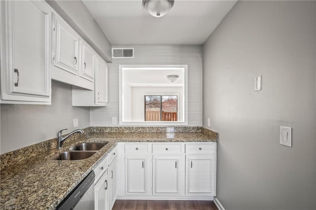 kitchen with dark stone counters, a sink, visible vents, and white cabinets