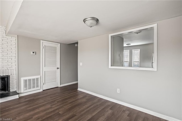 unfurnished living room featuring baseboards, a fireplace, visible vents, and dark wood finished floors