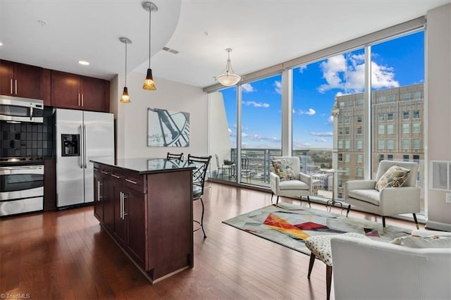 kitchen featuring dark hardwood / wood-style flooring, a kitchen island, pendant lighting, and appliances with stainless steel finishes