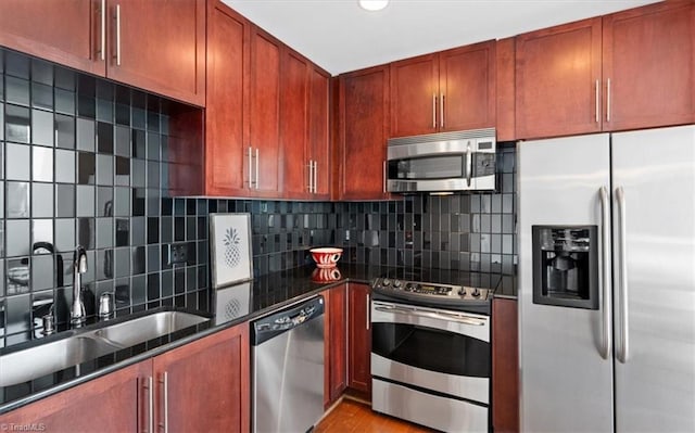 kitchen with decorative backsplash, stainless steel appliances, sink, light hardwood / wood-style flooring, and dark stone countertops