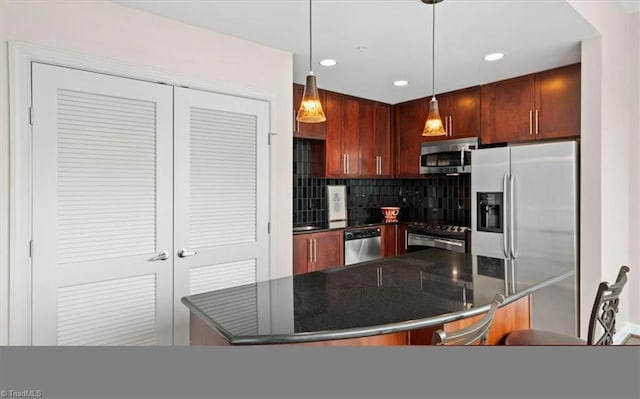 kitchen with backsplash, a kitchen bar, pendant lighting, and appliances with stainless steel finishes