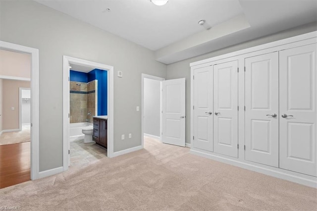 unfurnished bedroom with light carpet and connected bathroom