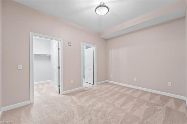 unfurnished bedroom with light colored carpet, a spacious closet, and a closet