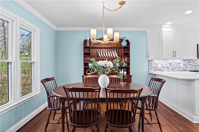 dining room featuring dark wood finished floors, crown molding, a notable chandelier, and baseboards