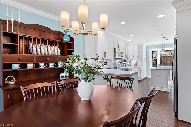 dining room with dark wood-type flooring, a notable chandelier, recessed lighting, and ornamental molding