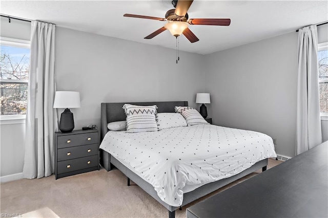 bedroom with light carpet, multiple windows, baseboards, and ceiling fan