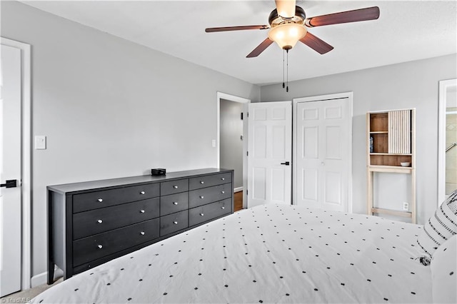 bedroom featuring ensuite bath, baseboards, a closet, and ceiling fan