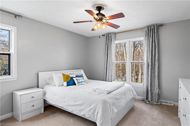 bedroom featuring ceiling fan, light colored carpet, visible vents, and baseboards