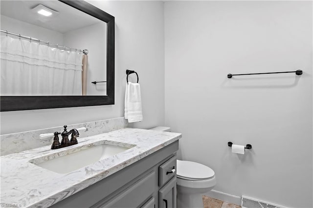 bathroom featuring vanity, baseboards, visible vents, tile patterned floors, and toilet