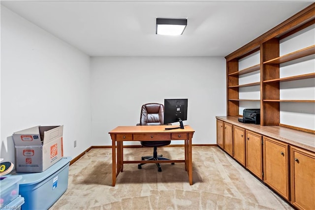 office area featuring baseboards and light carpet