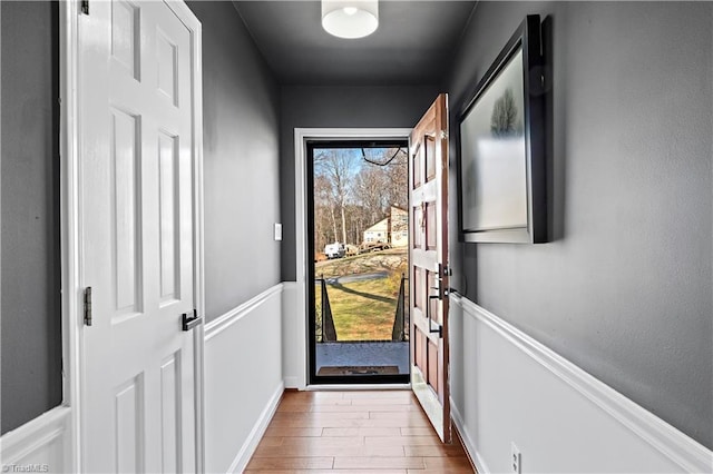 doorway to outside featuring baseboards and wood finished floors