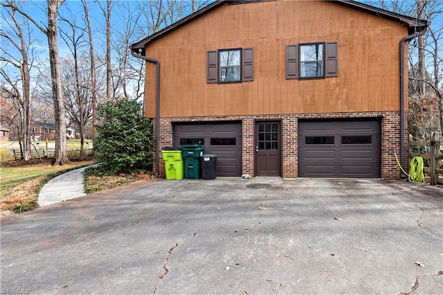 view of property exterior featuring aphalt driveway, brick siding, and a garage