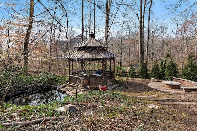 view of yard featuring a gazebo, a view of trees, and an outdoor fire pit