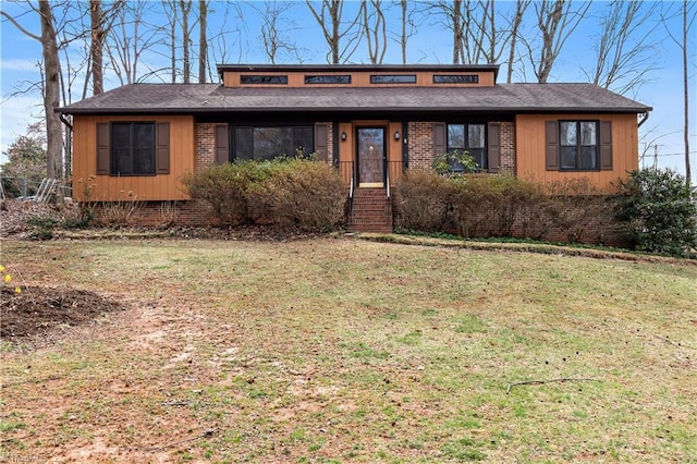 view of front of house with brick siding, a shingled roof, and a front lawn