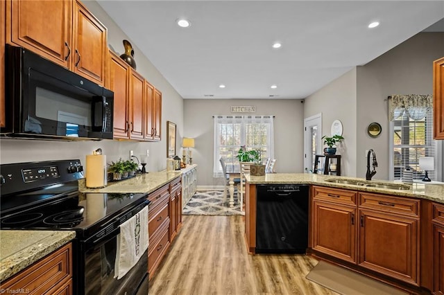 kitchen with a wealth of natural light, sink, light hardwood / wood-style flooring, and black appliances