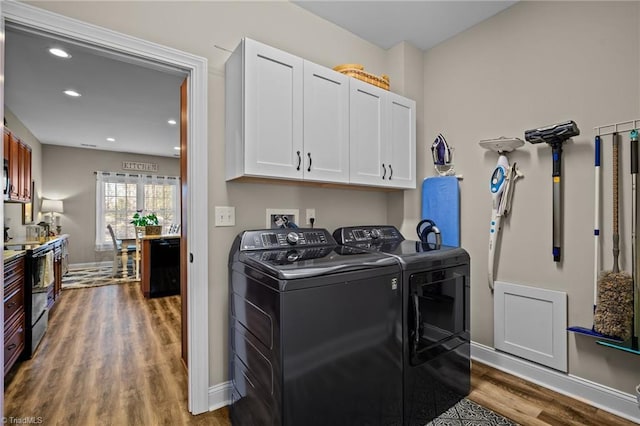 laundry room featuring dark hardwood / wood-style floors, washer and clothes dryer, and cabinets