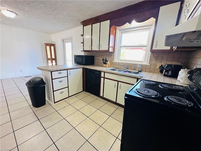 kitchen featuring exhaust hood, a peninsula, black appliances, light tile patterned flooring, and a sink