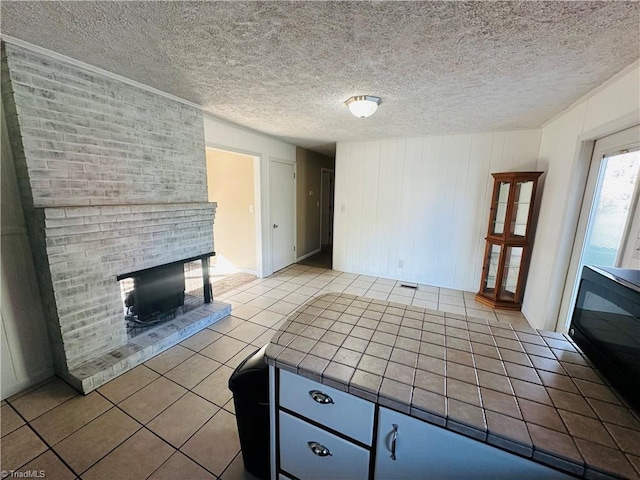 unfurnished living room featuring a textured ceiling, tile patterned flooring, and a brick fireplace