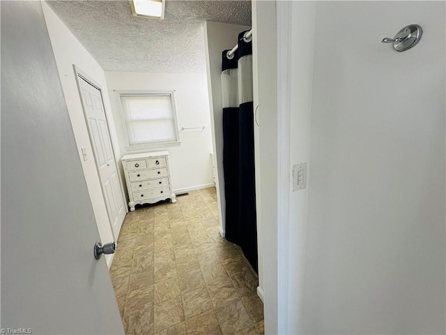 corridor with a textured ceiling and tile patterned floors