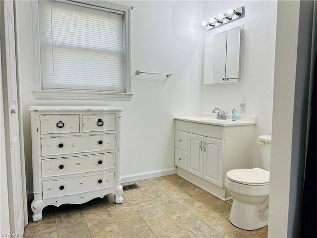 bathroom featuring toilet, vanity, baseboards, and visible vents