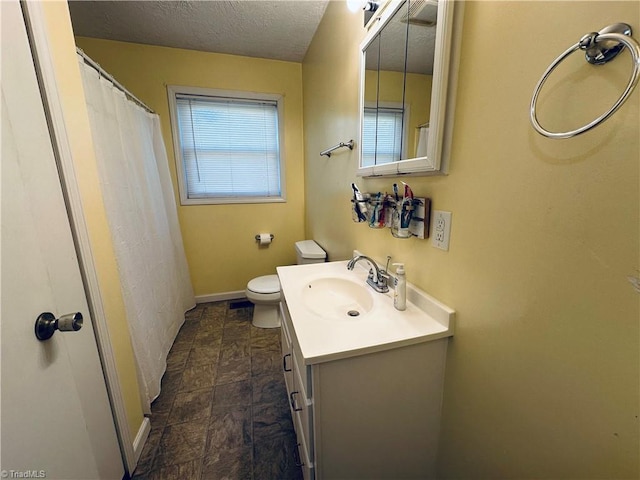 full bath with vanity, a textured ceiling, baseboards, and toilet