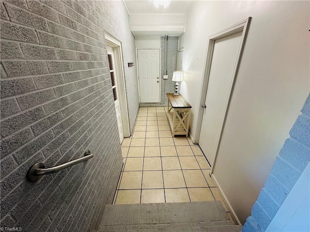 corridor with brick wall and light tile patterned flooring