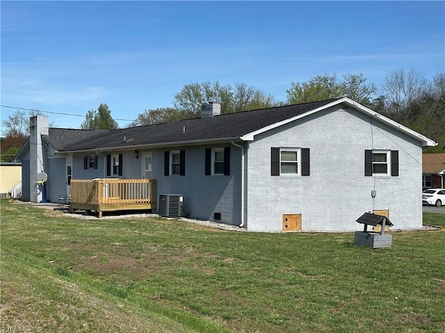 back of property featuring central air condition unit, a chimney, brick siding, a wooden deck, and a lawn