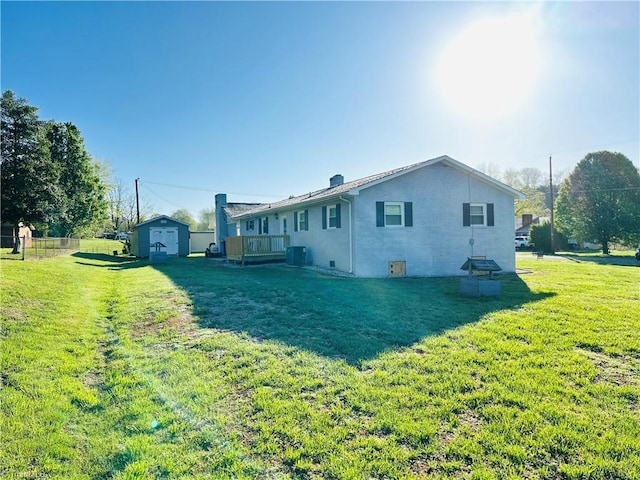 rear view of house with an outbuilding, central AC, a lawn, a storage unit, and a chimney