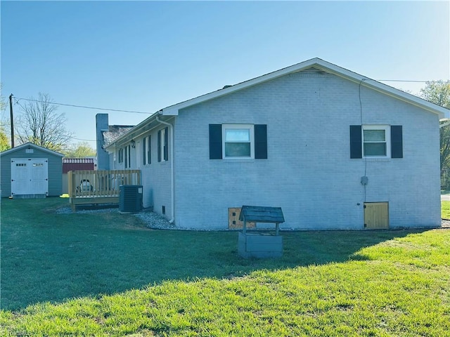 view of side of property featuring an outbuilding, a shed, central AC, a lawn, and brick siding