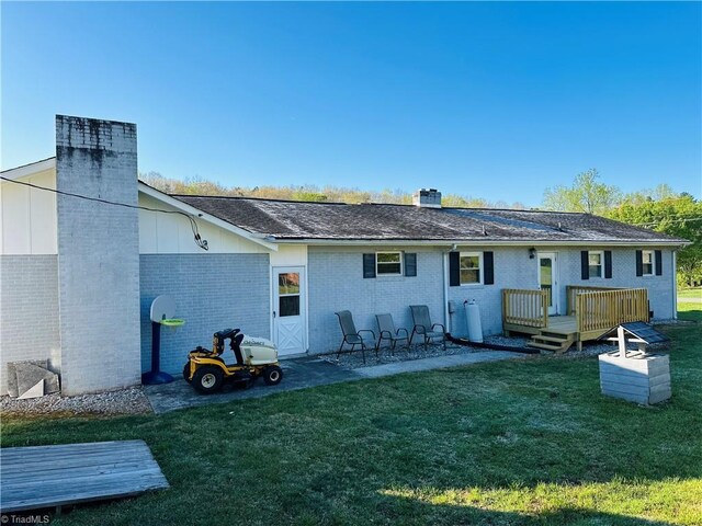rear view of house with a yard, brick siding, and a chimney