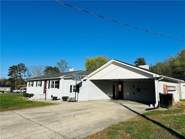 view of front facade featuring concrete driveway, an attached carport, and a front lawn