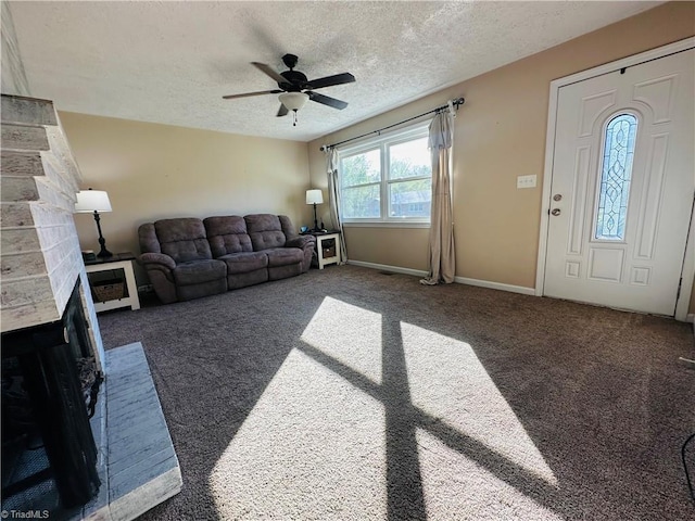 carpeted living area with ceiling fan, baseboards, a brick fireplace, and a textured ceiling