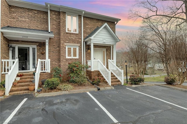 view of front facade featuring brick siding and uncovered parking